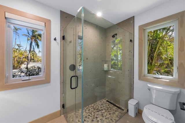 bathroom with a shower with door and toilet