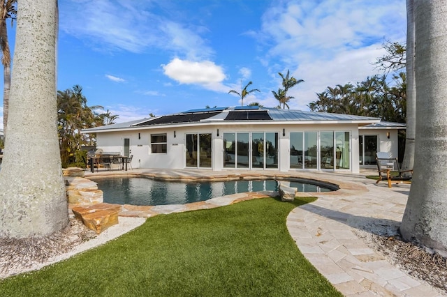 rear view of house with a lawn, a patio, and solar panels