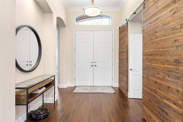 foyer entrance with dark hardwood / wood-style floors, crown molding, and a barn door