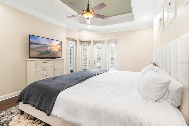 bedroom featuring wood-type flooring, access to exterior, ceiling fan, a tray ceiling, and crown molding