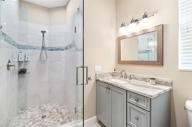 bathroom with a shower with shower door, toilet, and vanity