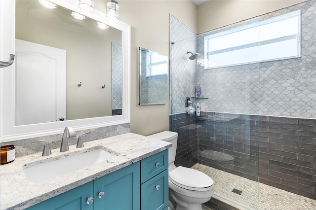 bathroom featuring toilet, vanity, and tiled shower