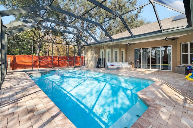 view of swimming pool featuring glass enclosure, a patio area, and ceiling fan