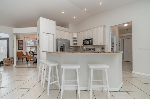 kitchen with stainless steel fridge with ice dispenser, white cabinetry, kitchen peninsula, vaulted ceiling, and light stone counters