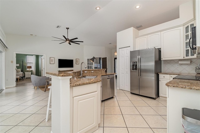 kitchen featuring white cabinets, stainless steel appliances, decorative backsplash, sink, and light tile patterned floors