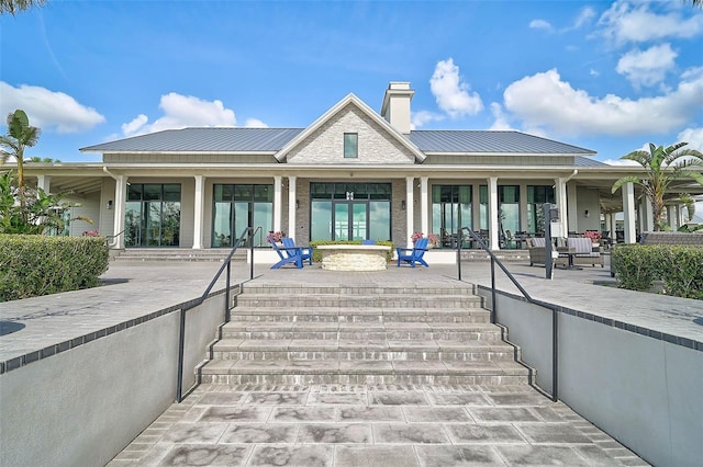 rear view of property with a patio area, a chimney, and metal roof