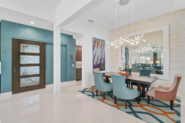 dining space featuring a towering ceiling, light tile patterned floors, and visible vents