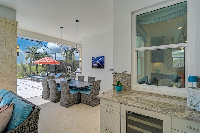 dining space featuring a sunroom, beverage cooler, and stone finish floor