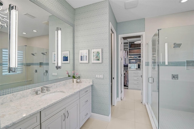 bathroom with a shower stall, a spacious closet, vanity, and tile patterned floors