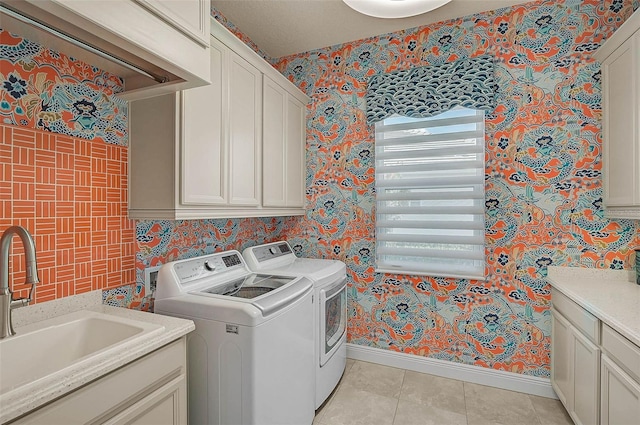 washroom featuring a sink, wallpapered walls, cabinet space, and washer and dryer