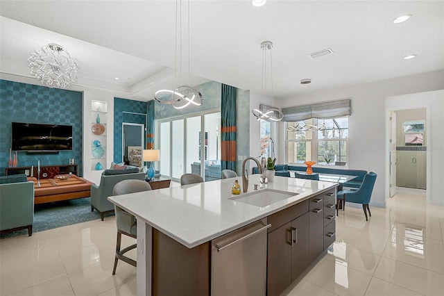 kitchen with a sink, open floor plan, hanging light fixtures, stainless steel dishwasher, and a center island with sink