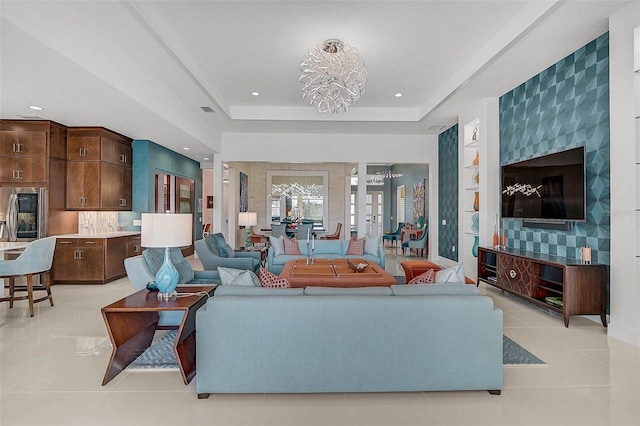 living area featuring a tray ceiling, french doors, light tile patterned floors, recessed lighting, and a chandelier