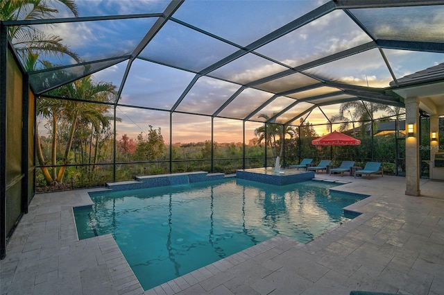 outdoor pool featuring glass enclosure, a patio area, and an in ground hot tub