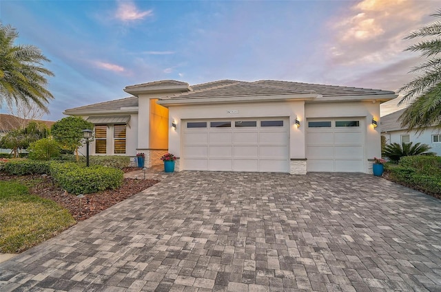 prairie-style house featuring decorative driveway, an attached garage, and stucco siding