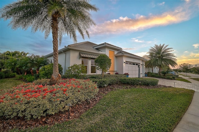 view of front of home featuring a garage, a front yard, decorative driveway, and stucco siding