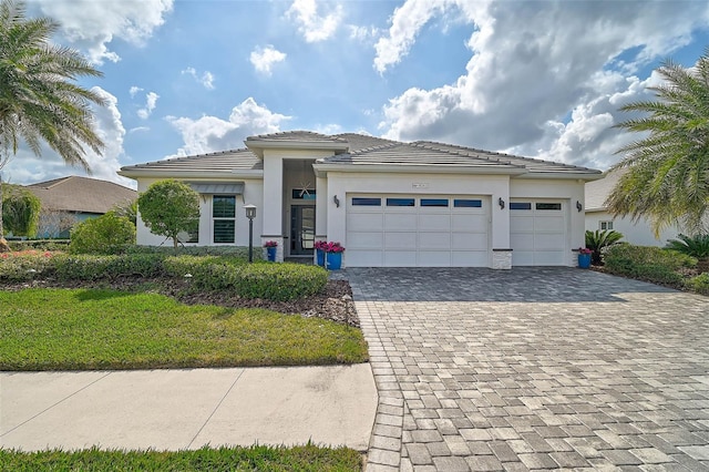 prairie-style home featuring a garage, decorative driveway, a tile roof, and stucco siding