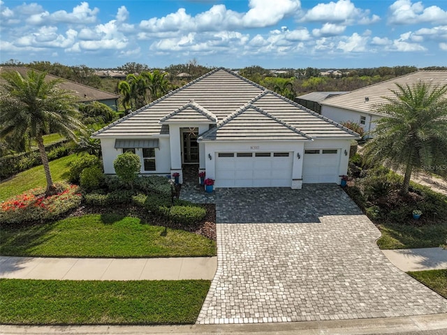 single story home featuring decorative driveway, a tile roof, an attached garage, and stucco siding