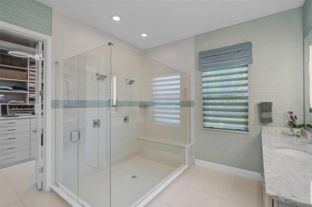 8261 Grande Shores Dr, Sarasota, FL 34240 - full bathroom featuring wallpapered walls, a stall shower, a spacious closet, double vanity, and tile patterned flooring