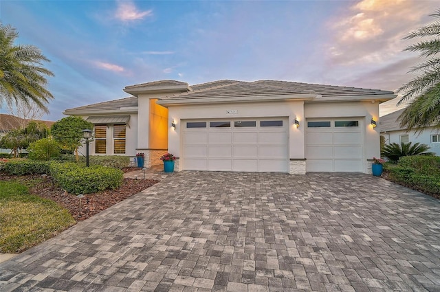 8261 Grande Shores Dr, Sarasota, FL 34240 - prairie-style home featuring decorative driveway, an attached garage, stucco siding, and a tiled roof