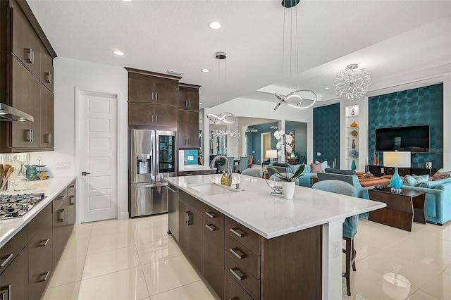 8261 Grande Shores Dr, Sarasota, FL 34240 - kitchen with stainless steel appliances, open floor plan, a kitchen bar, dark brown cabinets, and a center island with sink