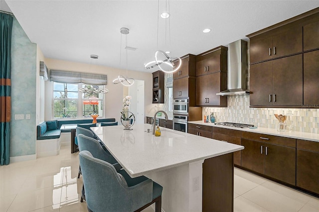 8261 Grande Shores Dr, Sarasota, FL 34240 - kitchen featuring wall chimney exhaust hood, light tile patterned flooring, a kitchen bar, backsplash, and appliances with stainless steel finishes