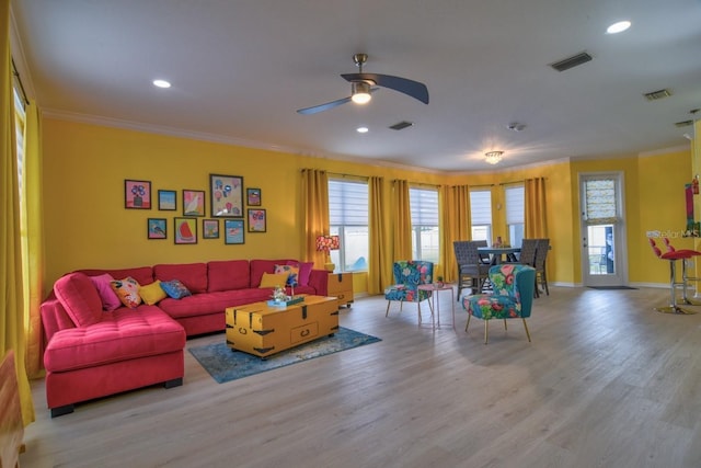 living room featuring ceiling fan, ornamental molding, and light wood-type flooring