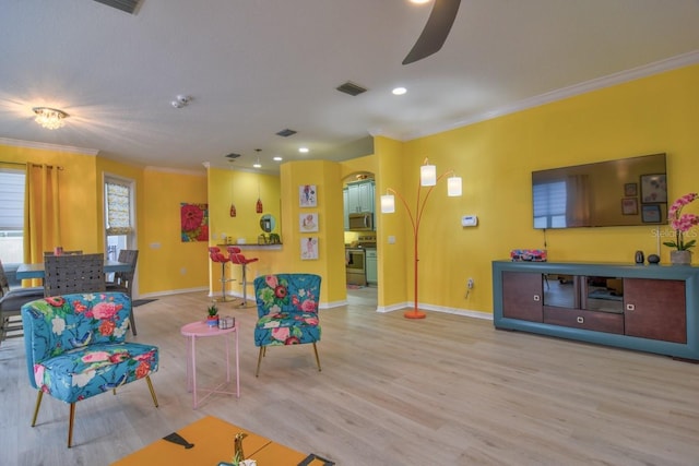 living room featuring light hardwood / wood-style flooring, ceiling fan, and ornamental molding