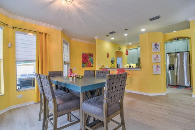 dining room featuring ornamental molding and light wood-type flooring