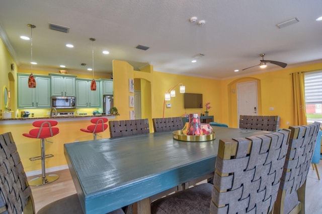 dining room with ceiling fan, crown molding, and light wood-type flooring