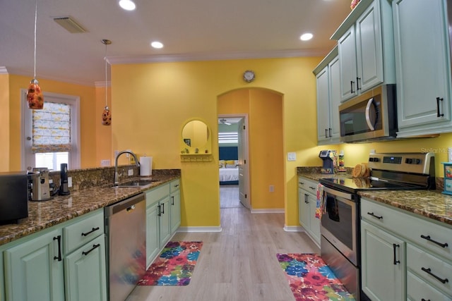 kitchen with sink, ornamental molding, appliances with stainless steel finishes, and pendant lighting