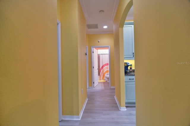 hallway with light wood-type flooring and ornamental molding