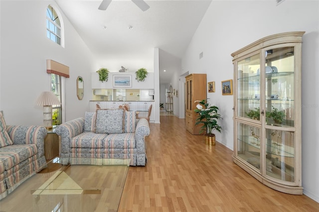 living room with a healthy amount of sunlight, light hardwood / wood-style floors, and a high ceiling