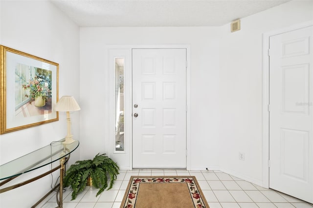 foyer entrance featuring light tile patterned floors and a textured ceiling