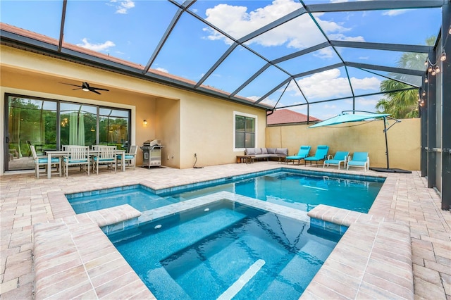 view of swimming pool with glass enclosure, an in ground hot tub, a patio, and ceiling fan