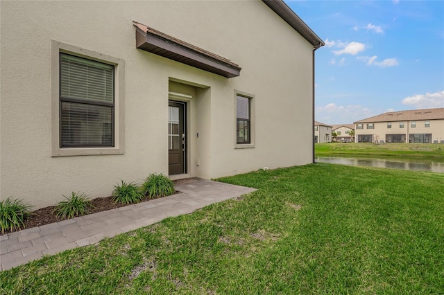 property entrance featuring a lawn and a water view