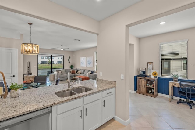 kitchen featuring white cabinetry, light tile patterned floors, stainless steel dishwasher, sink, and light stone counters