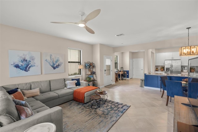 living room with ceiling fan with notable chandelier and light tile patterned floors