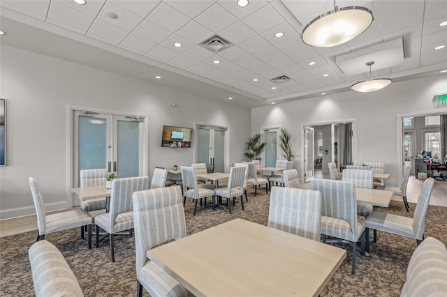 dining area featuring a drop ceiling, a towering ceiling, and french doors