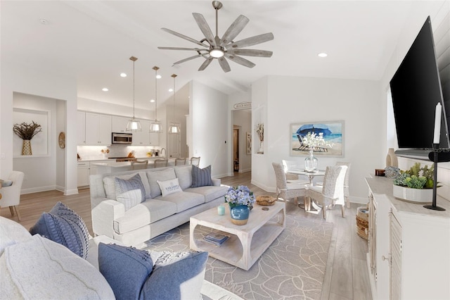 living room with ceiling fan, light hardwood / wood-style flooring, and lofted ceiling