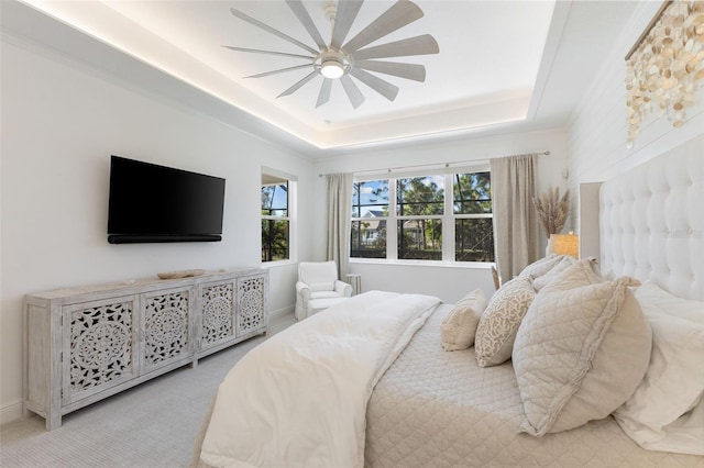 bedroom with light carpet, a tray ceiling, and ceiling fan