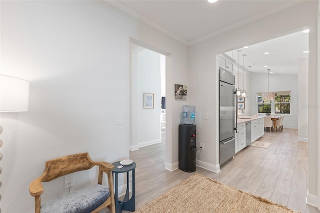 corridor with light hardwood / wood-style flooring and ornamental molding