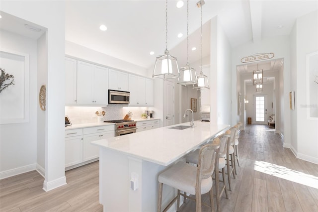 kitchen featuring decorative light fixtures, white cabinetry, stainless steel appliances, vaulted ceiling with beams, and sink