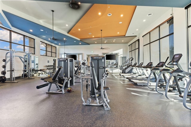 exercise room with a high ceiling and ceiling fan