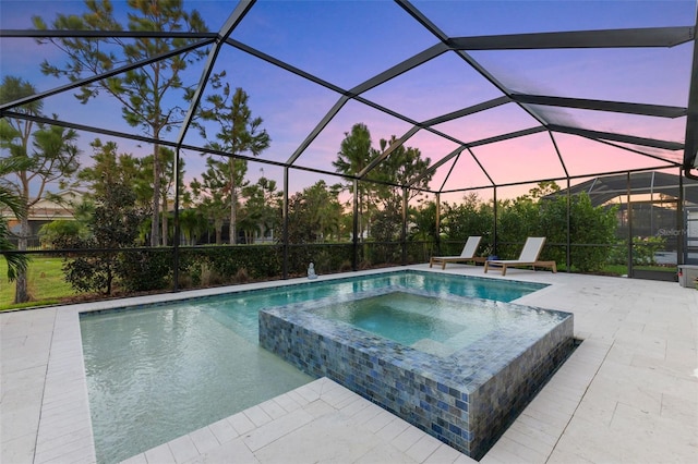 pool at dusk with an in ground hot tub, a patio, and a lanai