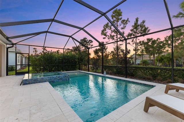 pool at dusk featuring an in ground hot tub, a lanai, and a patio area