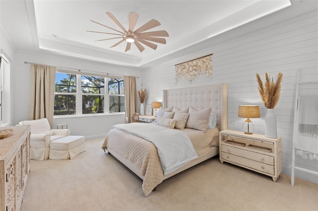 carpeted bedroom featuring ceiling fan and a tray ceiling