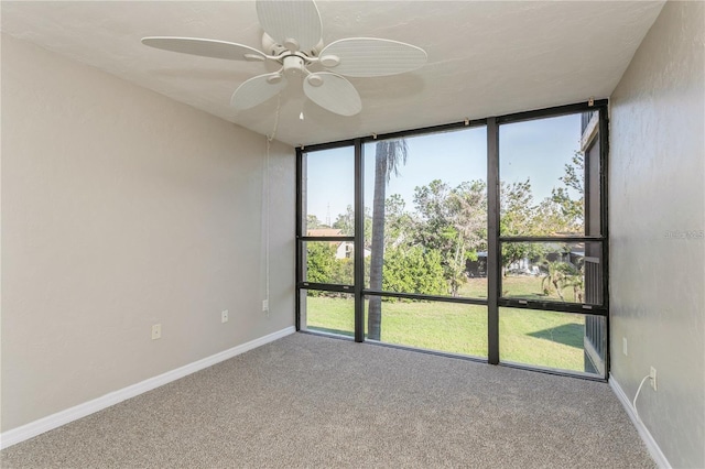 carpeted spare room featuring a wall of windows and ceiling fan