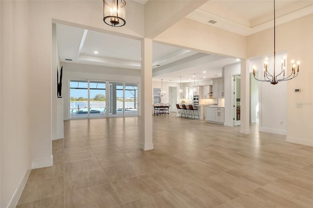 interior space featuring an inviting chandelier, light tile patterned floors, and a tray ceiling