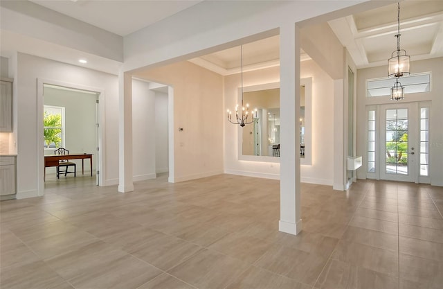 foyer entrance with a tray ceiling, light tile patterned floors, and a notable chandelier