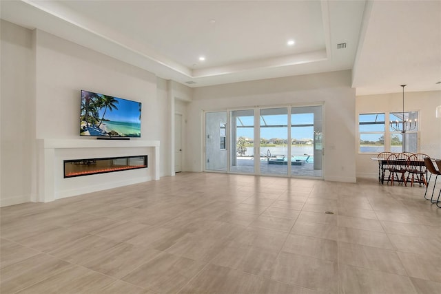 living room featuring light tile patterned floors, a notable chandelier, and a tray ceiling